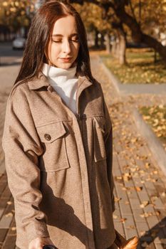 A stylish brunette woman walks around the autumn city. The season is autumn.