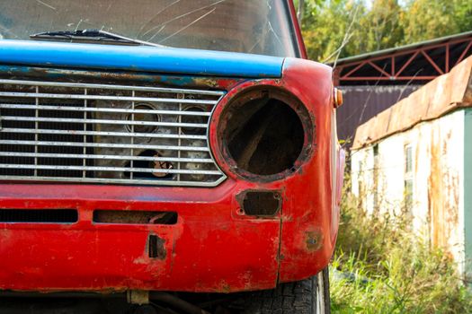 an old broken classic car abandoned on the street. front view. an old car. retro car close-up. a car without a headlight