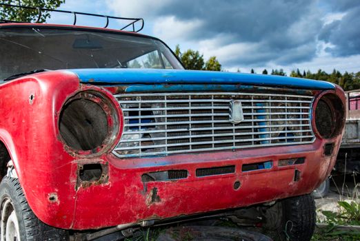 an old broken classic car abandoned on the street. front view of the shiny radiator grille. an old car. retro car close-up. a car without a headlight