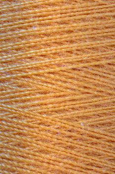 The macro texture of orange cotton thread on bobbin, close-up,