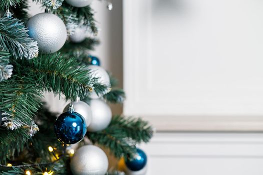 Christmas tree with blue and silver toys. Festively decorated Christmas tree with garlands. Symbol of the new year.