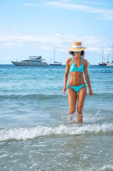 Woman with turquoise bikini and hat posing on a beach in Ibiza