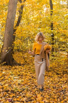 Walking woman on a fall day in the beautiful autumn park. Season and loneliness concept.
