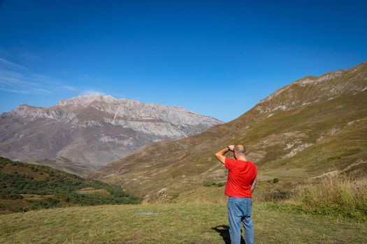 A man stands on top of a mountain with his arms outstretched