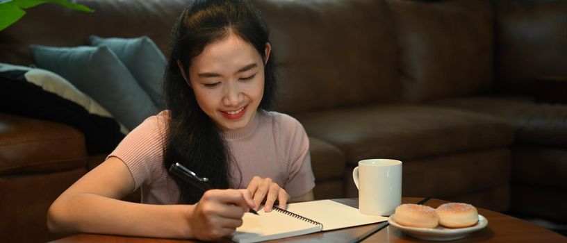 Pleasant woman in casual clothes making important notes, agenda plan planning daily appointment on her notebook.