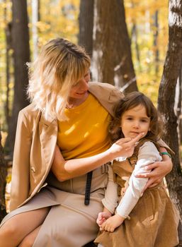 Mother and little daughter enjoying nice autumn day in a park. Season, family and children