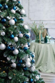 Christmas tree with blue and silver toys. Festively decorated Christmas tree with garlands. Symbol of the new year.