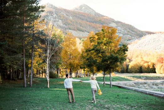 Man and woman walk through the park, overlooking the mountains. Back view. High quality photo