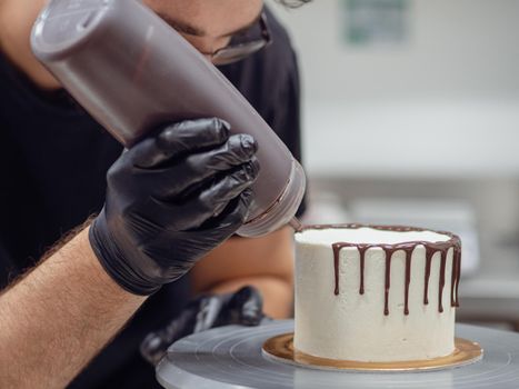 unrecognizable worker preparing a sweet dripping choco cake and berries