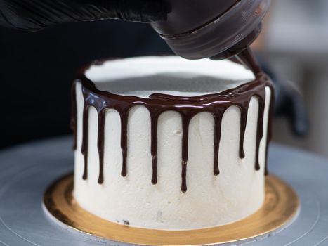 unrecognizable worker preparing a sweet dripping choco cake and berries