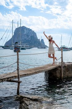 Brunette woman with hat and light beige dress on Ibiza pier