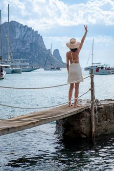Brunette woman with hat and light beige dress on Ibiza pier
