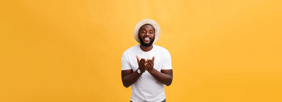 Portrait of handsome young african guy smiling in white t-shirt on yellow background.