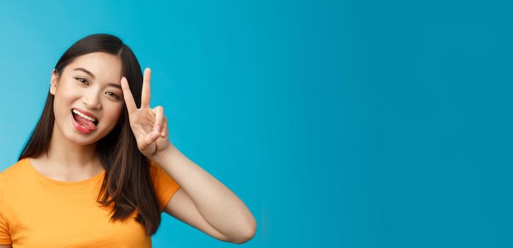 Close-up modern cute asian urban girl show tongue tilt head joyfully, express positive happy mood, make peace victory sign, smiling broadly, staying optimistic, excited participate lgbt pride.