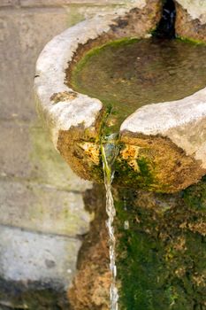 An old stone faucet with fresh water at penteli mountain in Greece.