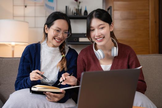 Two asian students learning together online with a laptop and tutor together at home.