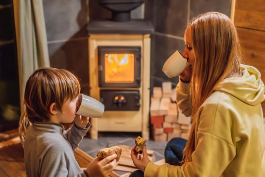 Mom and son spend time by the fireplace in Glamping. Rest in the mountains in Glamping. Cozy fireplace in a mountain house.