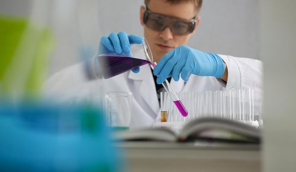 Scientist in protective gloves holding test tube of purple liquid. Laboratory research of poisonous liquids concept