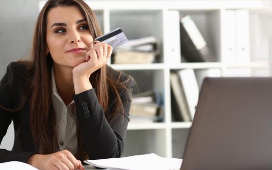 Happy pensive office worker holding bank credit card. Online shopping banking and online shopping