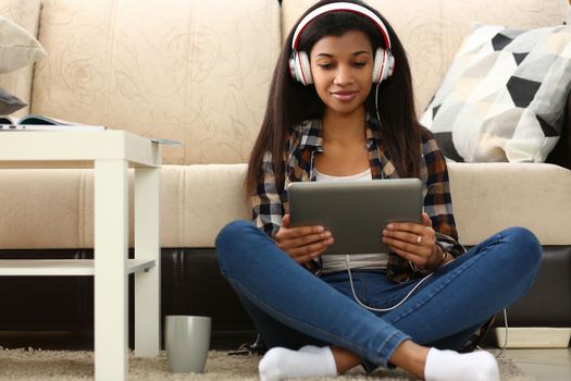 Learn foreign language online at home through application. Focused mixed race woman and remote female student sitting on floor in headset holding tablet pc