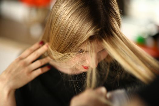 Young blonde woman demonstrates regrown hair roots. Closeup of woman head and long hair