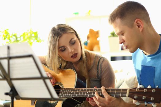 Man conducts guitar lessons for woman. Extracurricular tutoring hobby or creative music lessons