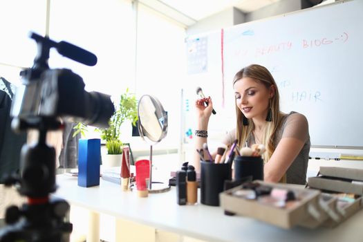 Young female blogger is recording tutorial video for blog about cosmetics. Maintaining an online blog and video blog about makeup and cosmetics