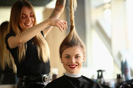 Professional female hairdresser stylist cuts hair of female client in salon. Beauty salon business concept