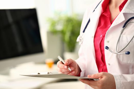 Hands of doctor hold clipboard and write down results of examination with pen. Full medical comprehensive examination of patient and health insurance
