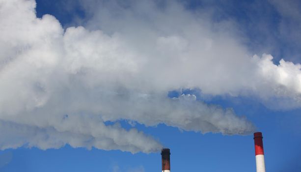 Chimney of factory plant against blue sky. Thermal condensing power plant concept