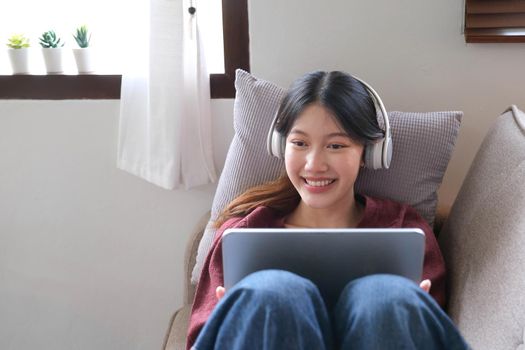 Attractive smiling young woman using tablet and listen music on sofa at home. lifestyle concept..