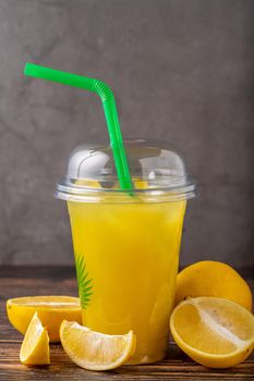 Lemonade in a take away glass with cut lemon next to it on wooden table