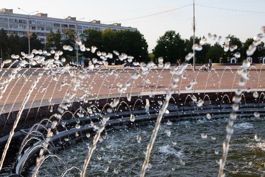 Splashes of water in the fountain at sunset close up