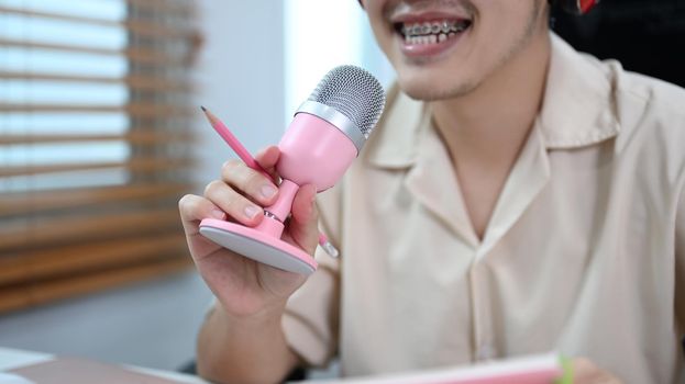 Image of radio host using microphone and laptop to recording podcast in home studio. Radio, podcasts and technology concept.