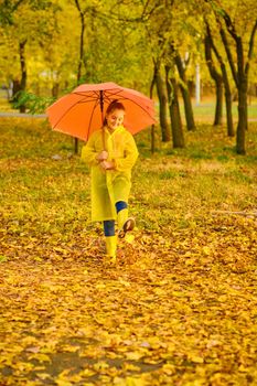 Happy child in the rain. Funny kid playing outdoors and having fun enjoying weather in autumn day in park