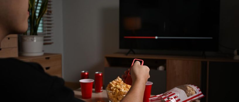 Man enjoy eating popcorn and watching movie on couch at home. Entertainment and leisure activity concept.