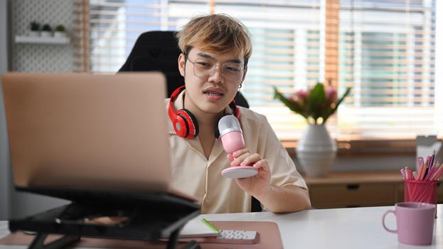 Image of radio host using microphone and laptop to recording podcast in home studio. Radio, podcasts and technology concept.