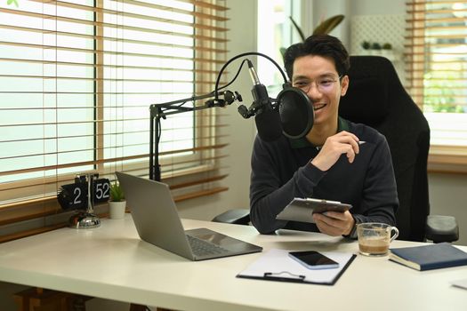 Image of radio host using microphone and laptop to recording podcast in home studio. Radio, podcasts and technology concept.