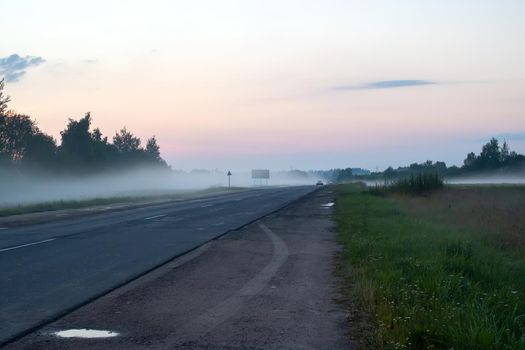 Fog on a country road at sunset close up