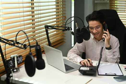 Image of radio host using microphone and laptop to recording podcast in home studio. Radio, podcasts and technology concept.