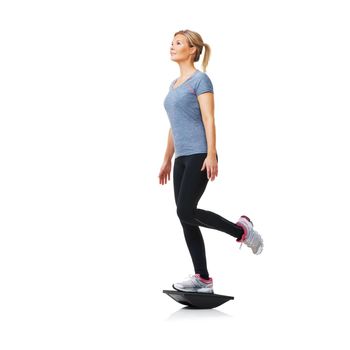 Balancing on her bosu - Health Fitness. A pretty young blond standing on a balance board while isolated on white
