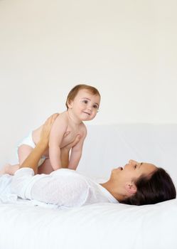 Bonding with my baby. A young mother lying on her back and holding up her baby girl while laughing