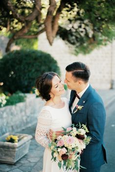 Bride and groom hugging smiling at each other under a tree. High quality photo