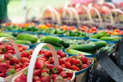 Strawberries for sale on vegetables market. Raw juicy strawberry in wooden basket standing on market display with other fruit and berry on background. Seasonal sweet berry