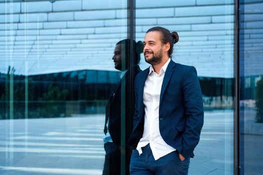 Successful businessman in suit with beard standing near office building confidently looking away. Hispanic male business person side view portrait. Free space. Modern Business people