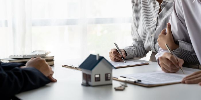 Real estate agent with couple closing a deal and signing a contract