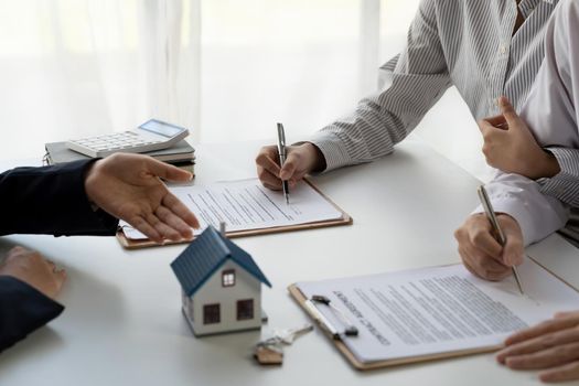 Real estate agent with couple closing a deal and signing a contract