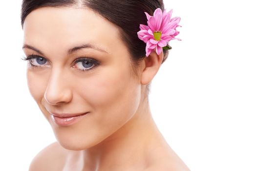 Discovering the essence of beauty. A beautiful brunette smiling at the camera with a pink flower in her hair