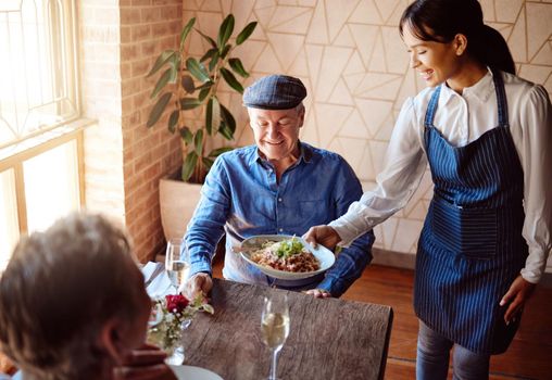 Love, food and old couple in restaurant with waiter on date for romance, happy and marriage. Retirement, fine dining and luxury with old man and woman at table for dinner service, wine and relax.
