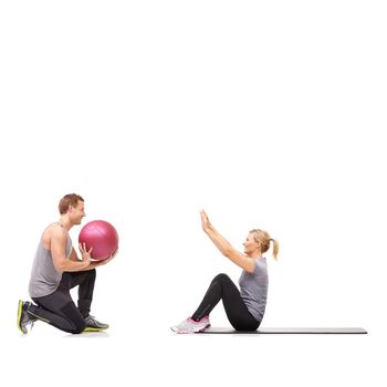 Passing the ball. A man and woman exercising their abs by passing a medicine ball to each other